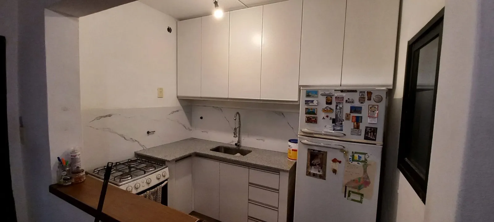 Cocina remodelada con muebles blancos y piso claro