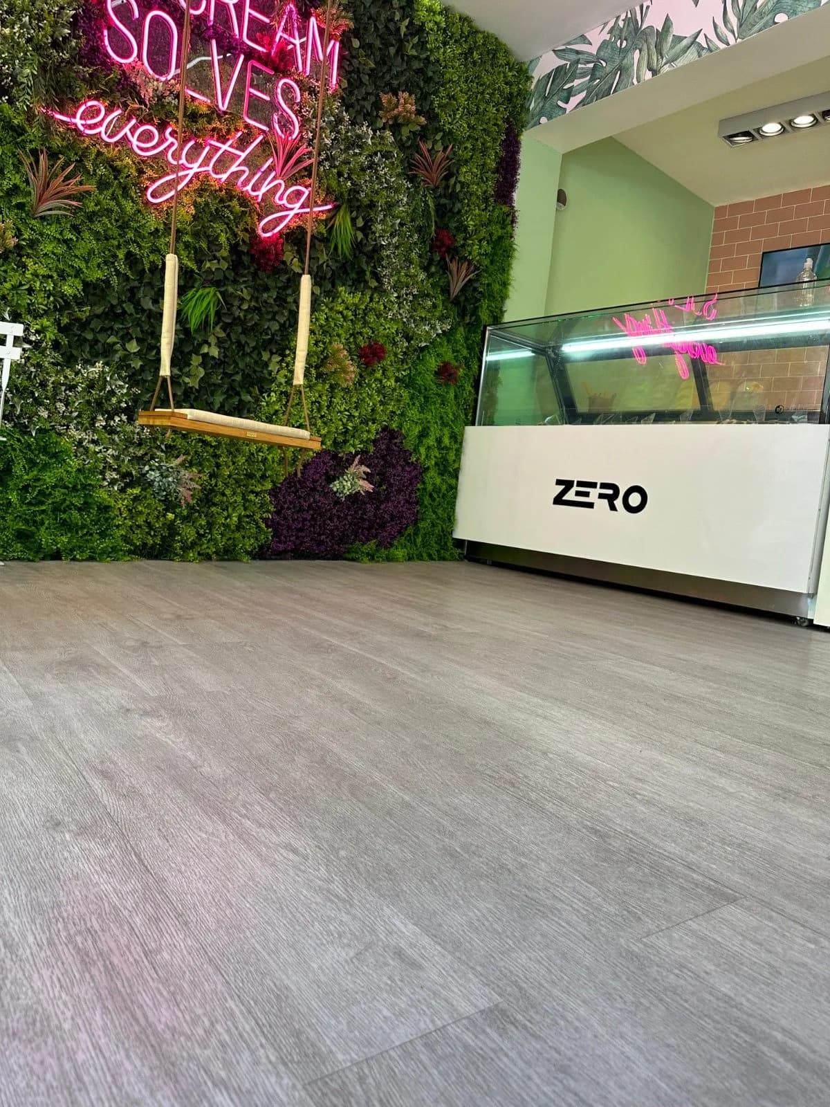 Local comercial con piso vinílico claro y pared vegetal