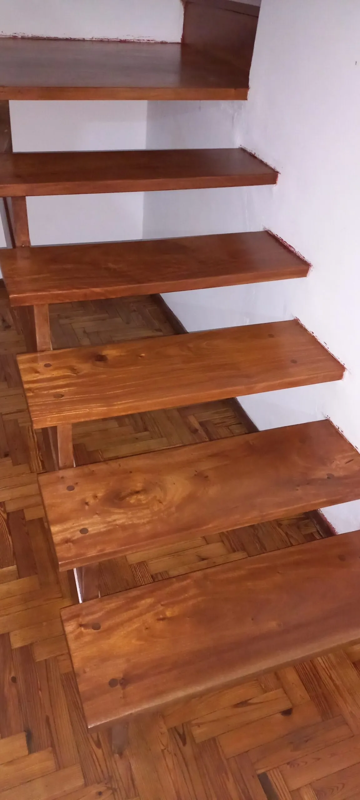Escalones flotantes de madera maciza sobre pared blanca
