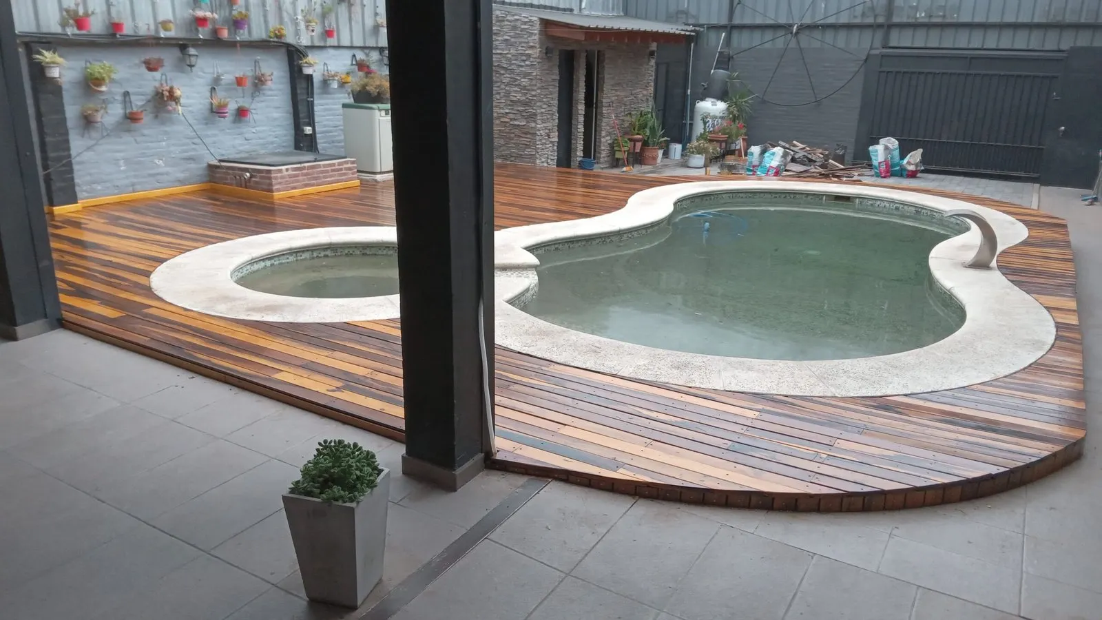 Deck de madera que rodea una pileta con solárium
