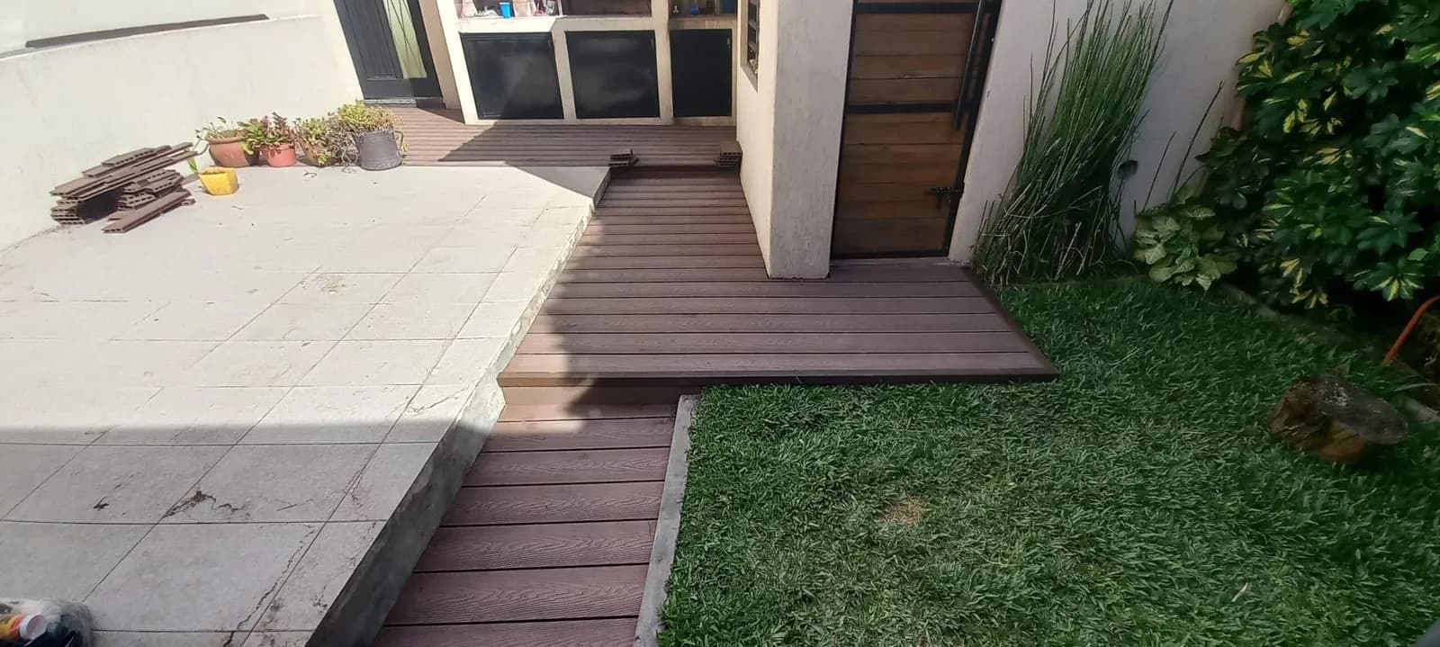 Deck de madera con escalón que conecta la casa con el jardín